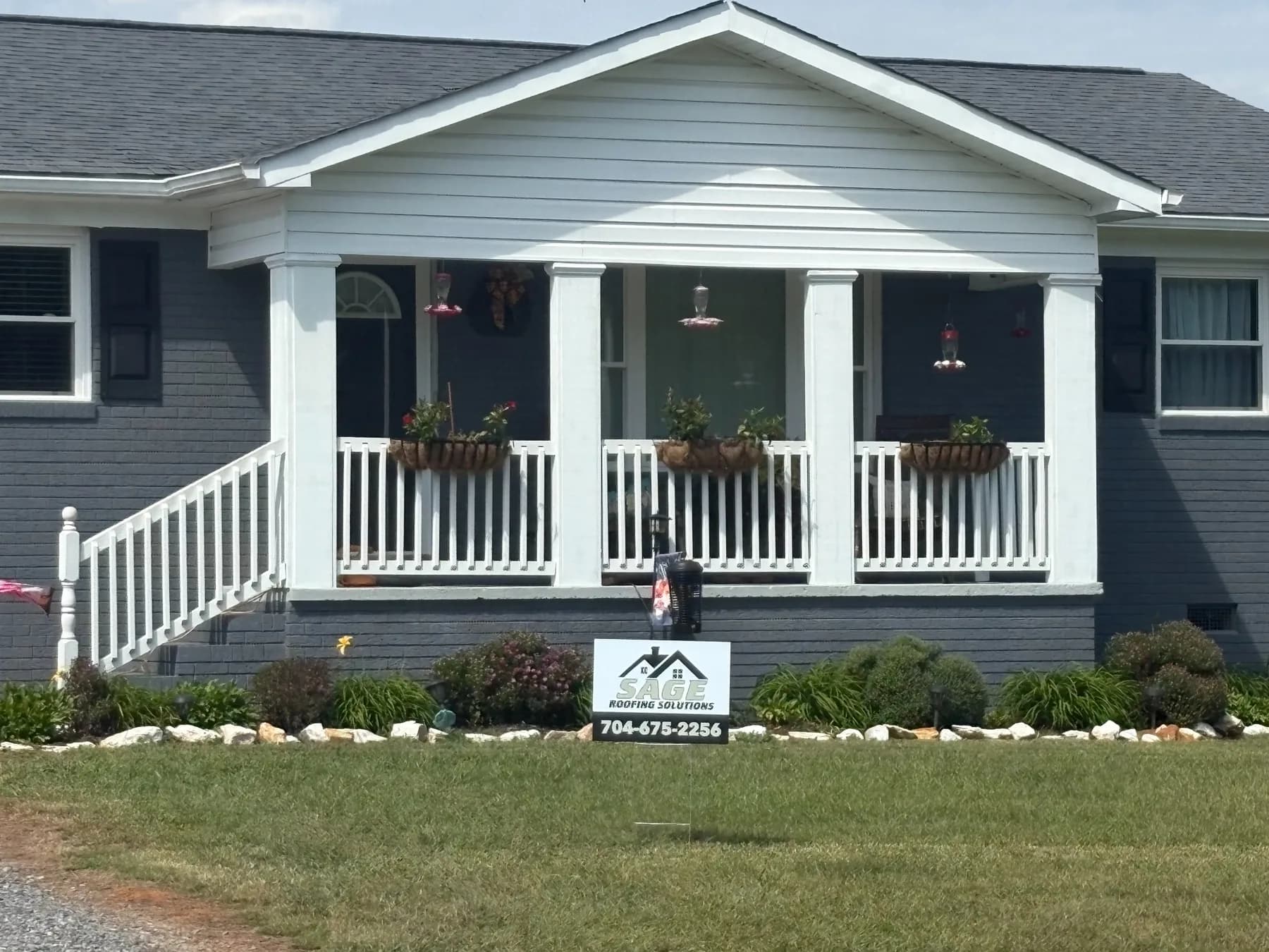 Finished home exterior with Sage Roofing Solutions yard sign